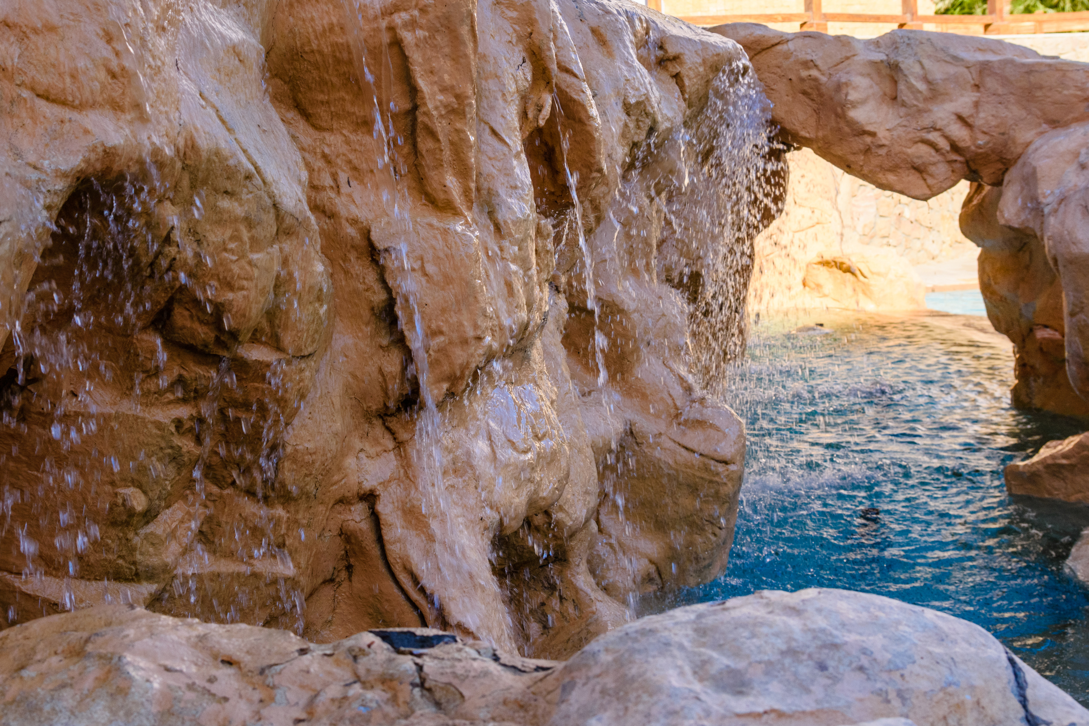 Small waterfall with turquoise water in hotel pool
